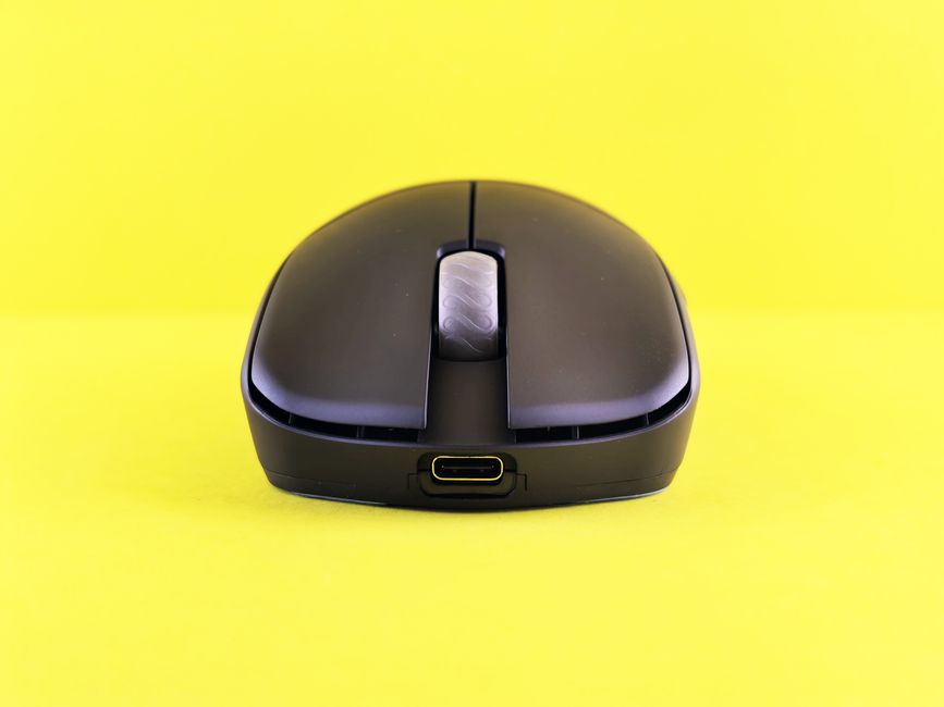 Modern wireless mouse with USB-C port on a bright yellow backdrop, highlighting its sleek design and functionality.